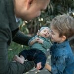 Chłopiec na dworze tuli nowo narodzone rodzeństwo