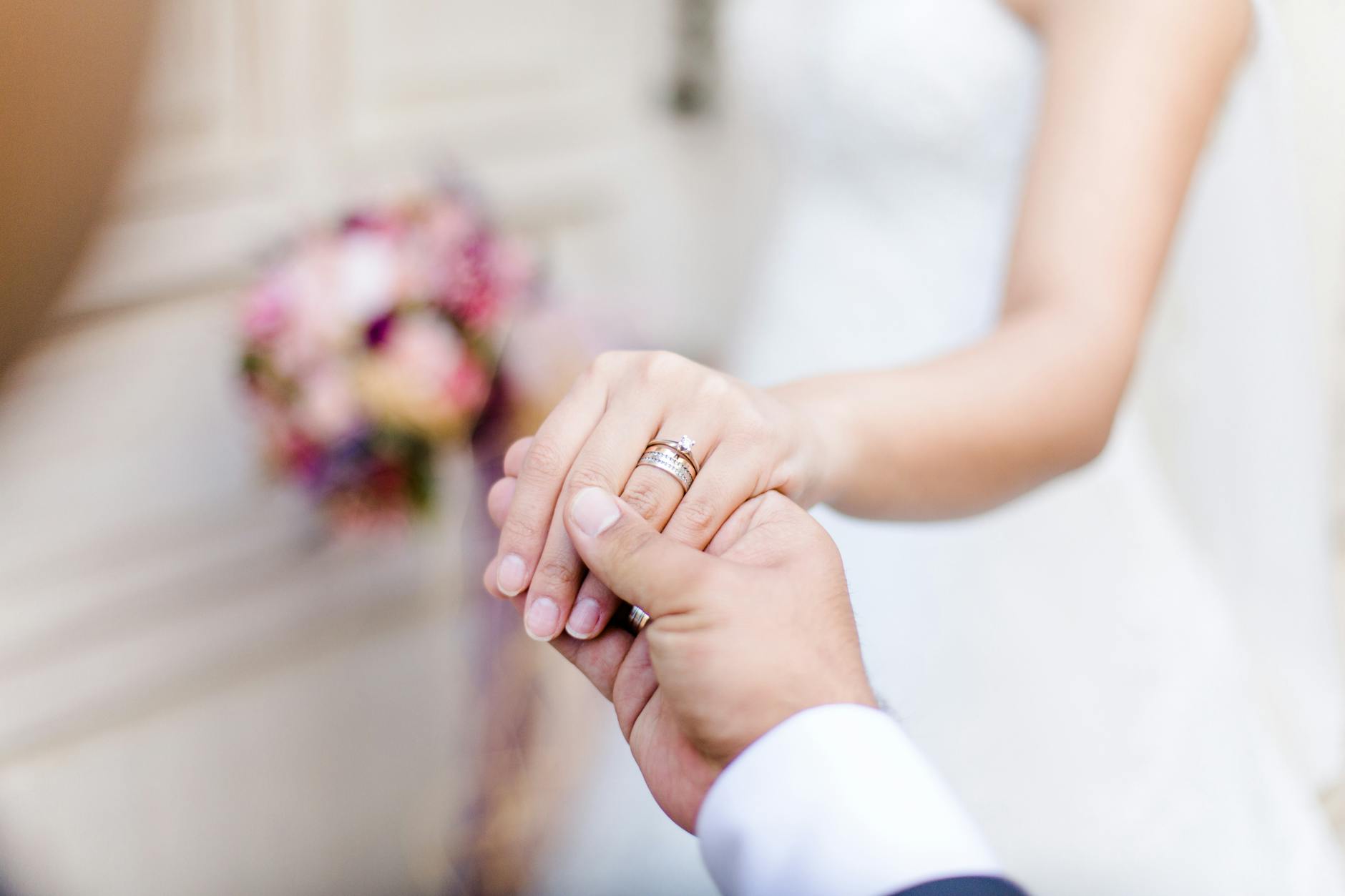 Para młoda trzyma się za ręce, zbliżenie na obrączki ślubne