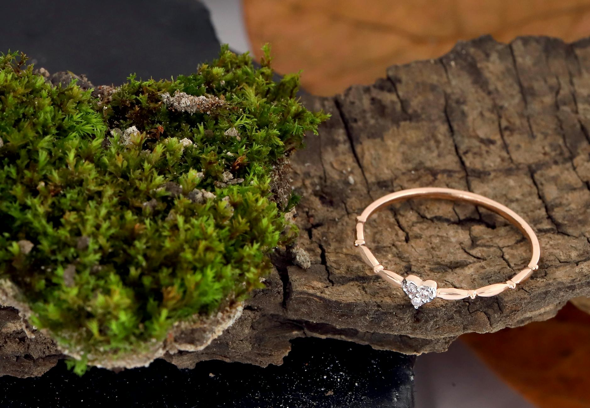 Pierścionek w kształcie serca z różowego złota na korze z zielonym mchem